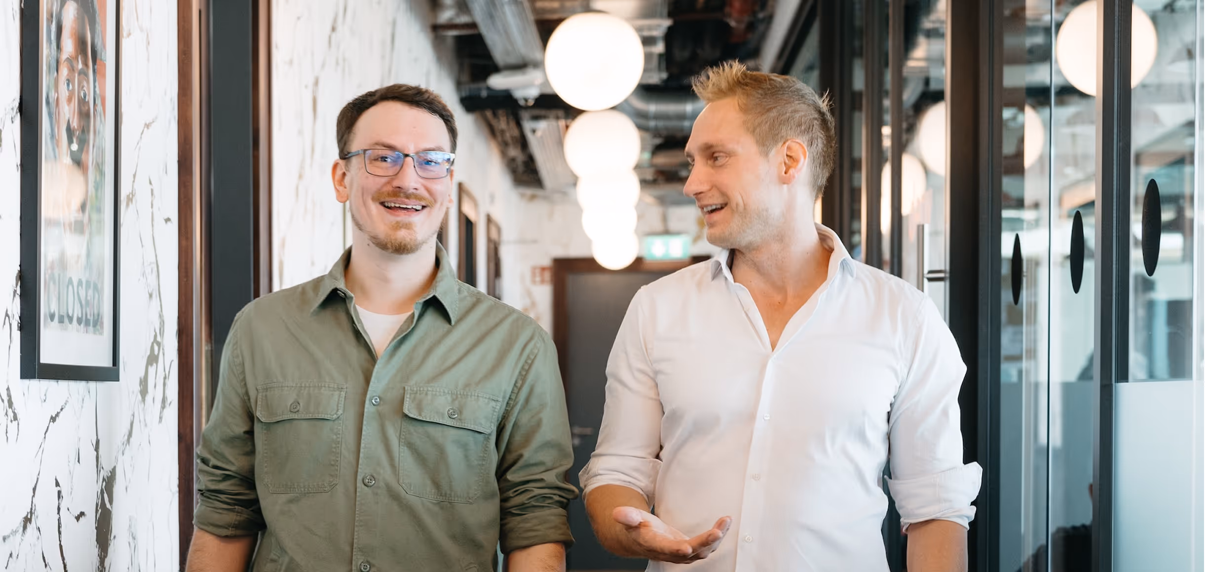 Zwei OneCode-Entwickler im Büro, im Gespräch über laufende Softwareprojekte – Sinnbild für Teamgeist und Ownership-Mentalität.