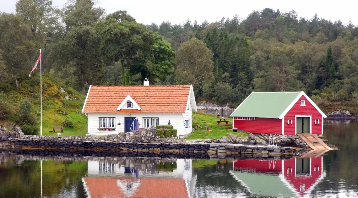 Illustrasjonsfoto av en fritidsbolig med naust langs kysten av Norge