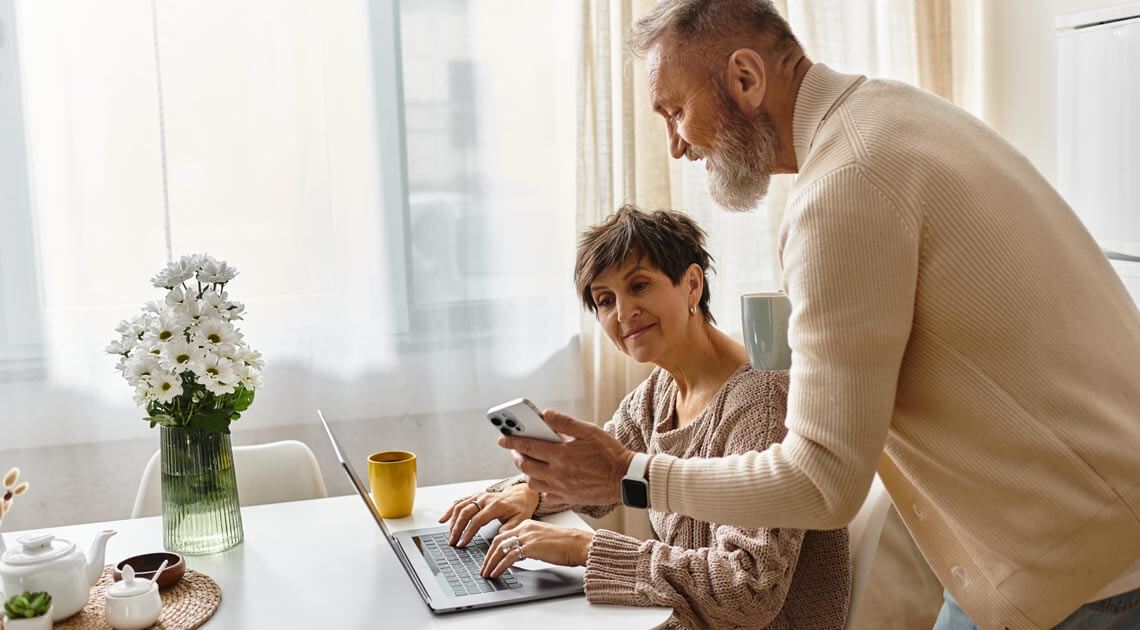 Middelaldrende par som ser på mobil og pc