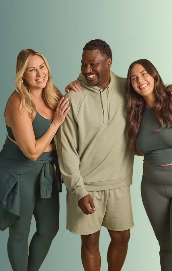Three adults smiling and standing closely together against a green gradient background, dressed in green casual and athletic clothing.