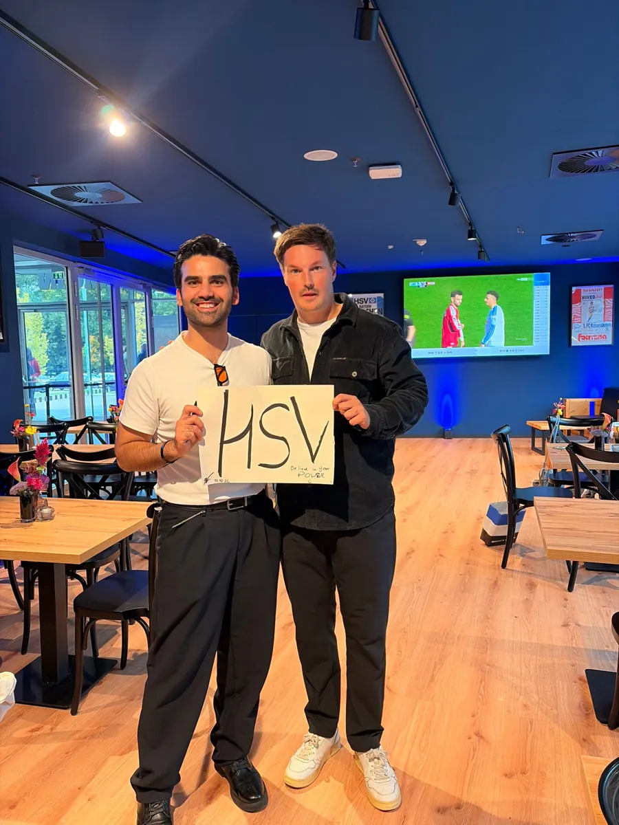 Zauberer Elias Noro mit HSV-Trainer Merlin Polzin und einem HSV-Schild
