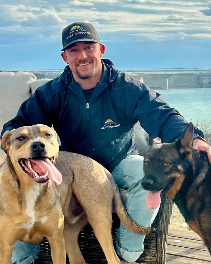 A man smiles with his hands on two large dogs.