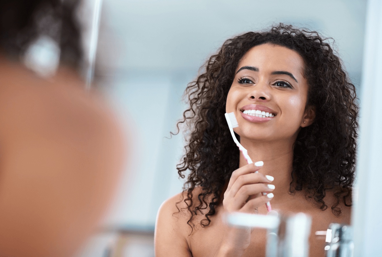A beautiful woman looks in the mirror as she takes care of her veneers from the best dentist in Naperville