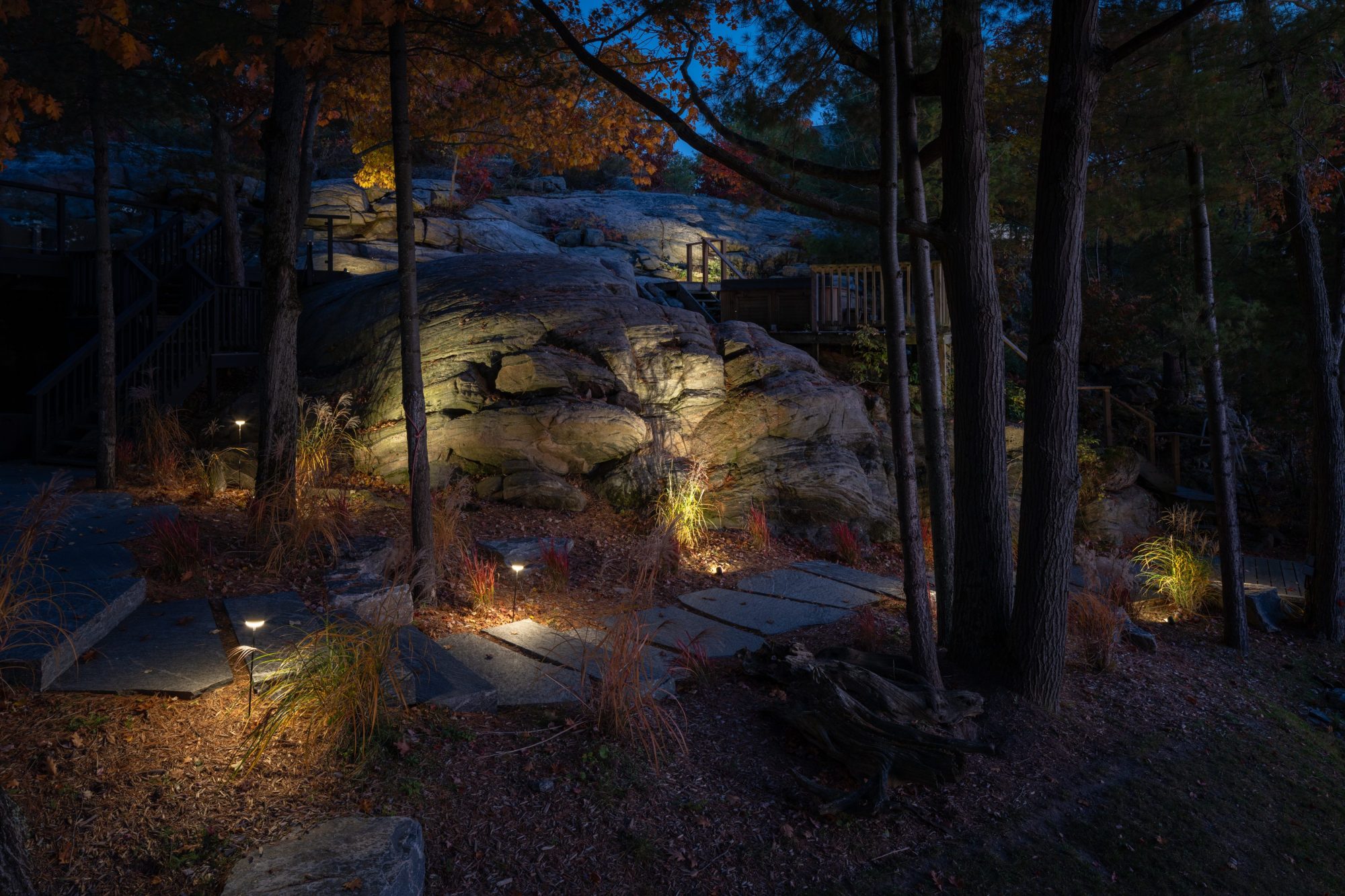 Granite outcrop and stone path lit with landscape lighting at night