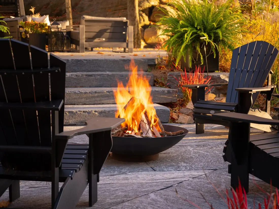 Stone steps and fire pit with Muskoka chairs on a flagstone patio