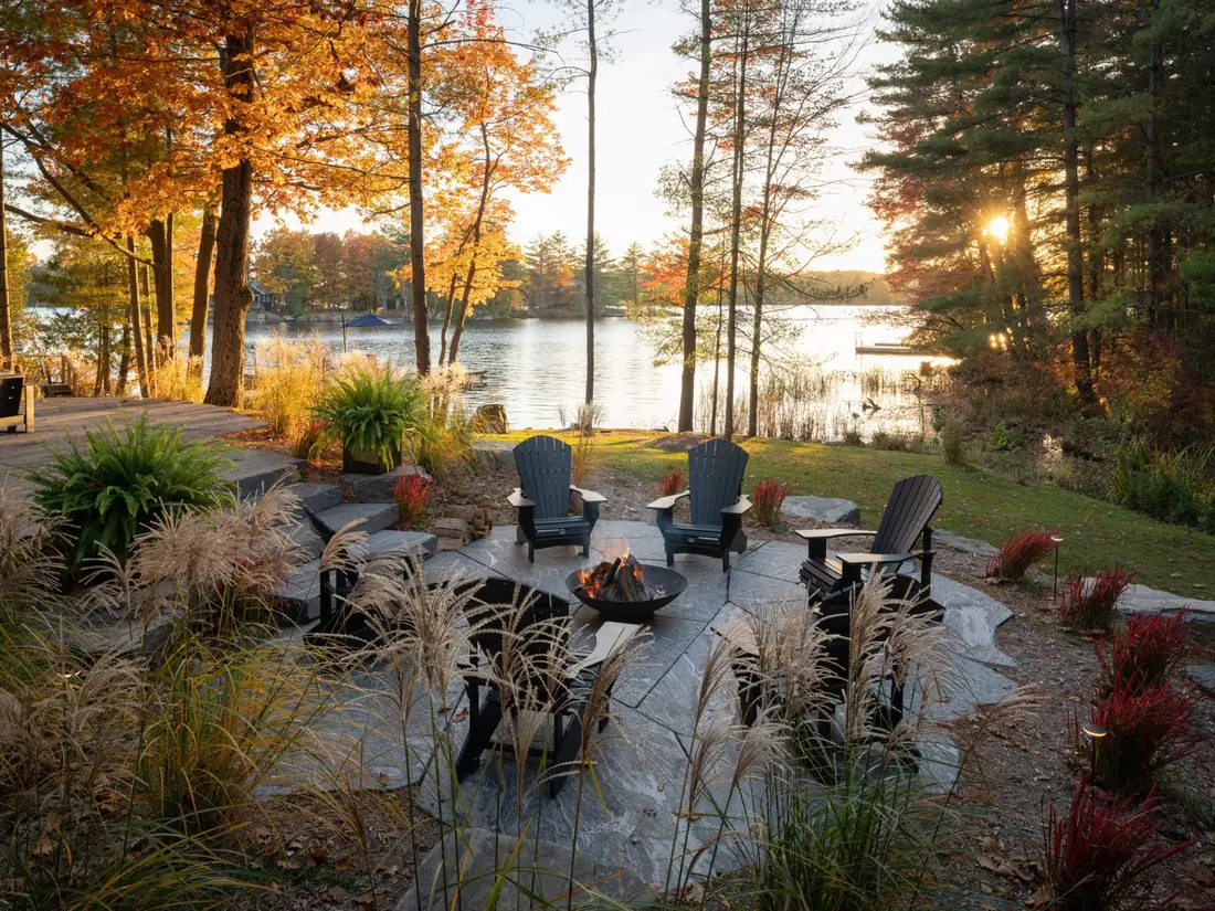 Flagstone fire pit terrace with Muskoka chairs at sunset on the lake in autumn