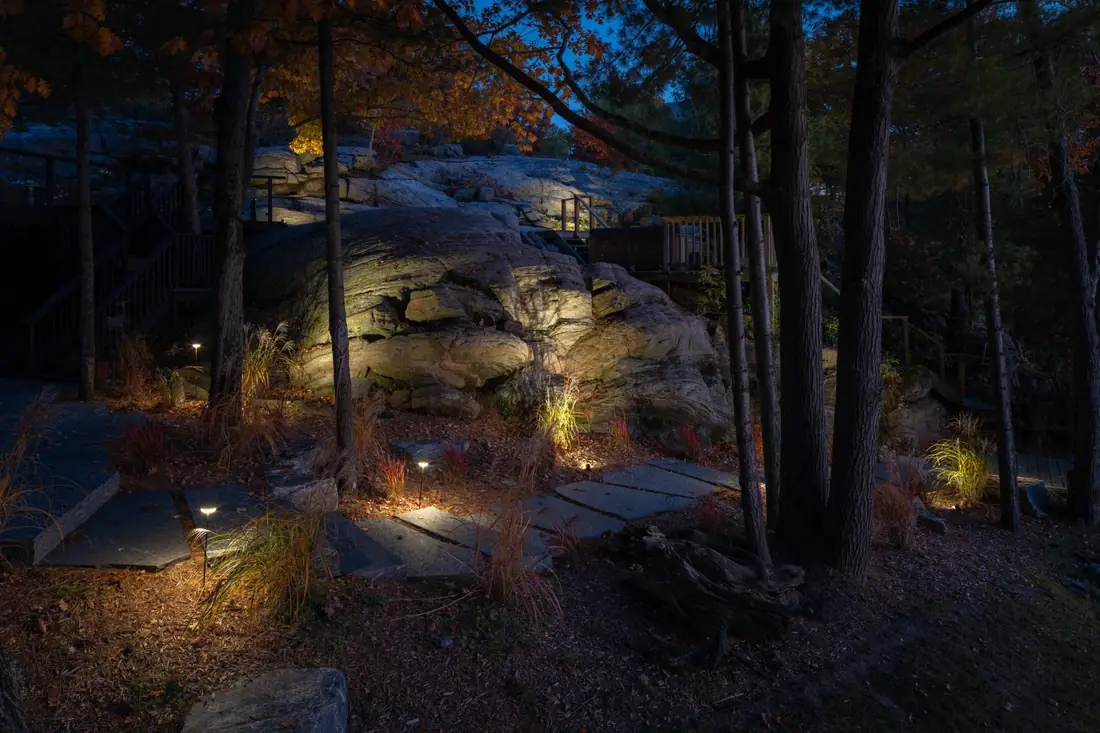 Granite outcrop and stone path lit with landscape lighting at night