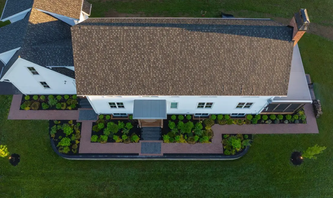 Aerial view of a farmhouse with planted beds and paver walkways