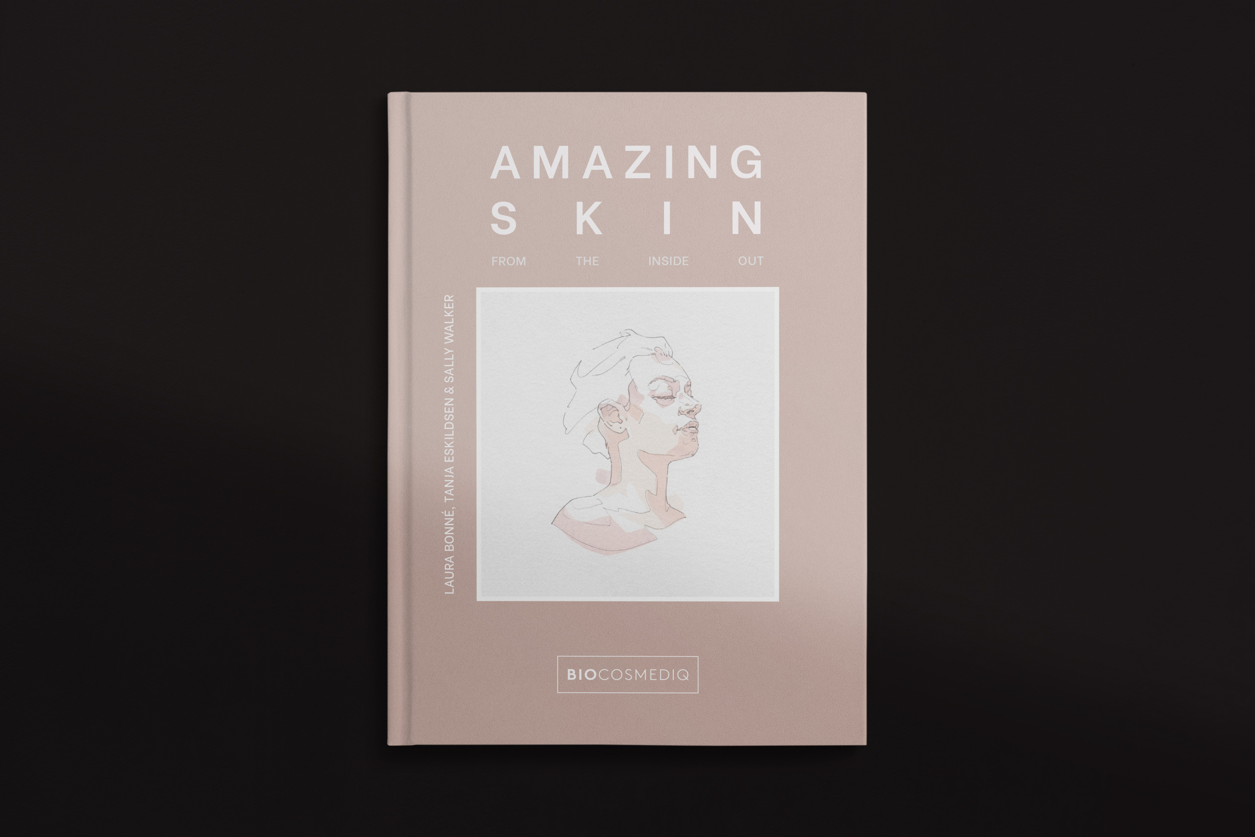 Flat lay of a pink hardcover book titled “Amazing Skin: From the Inside Out,” featuring minimalist white typography and a central sketch-style illustration of a woman’s face in profile. Authors listed on the spine are Laura Bonné, Tanja Eskildsen, and Sally Walker. The book is published by BIOCOSMEDIQ, with their logo displayed in a white-outlined box near the bottom.