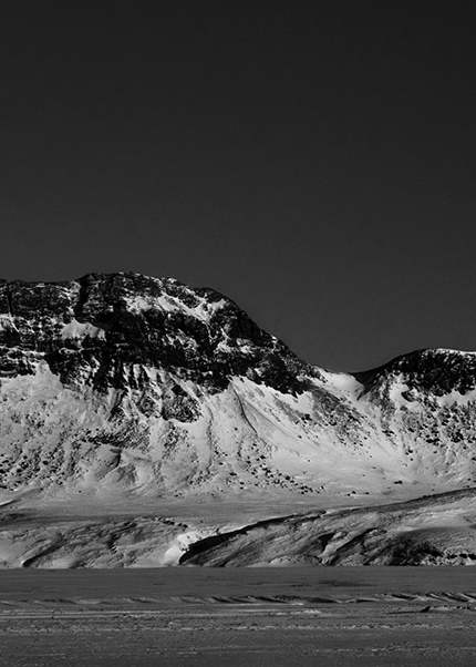 Black and white image of a snow-covered mountain ridge in Iceland under a dark sky.