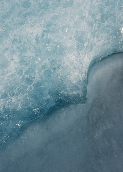 Close-up photograph of blue glacial ice in Iceland showing textured patterns.