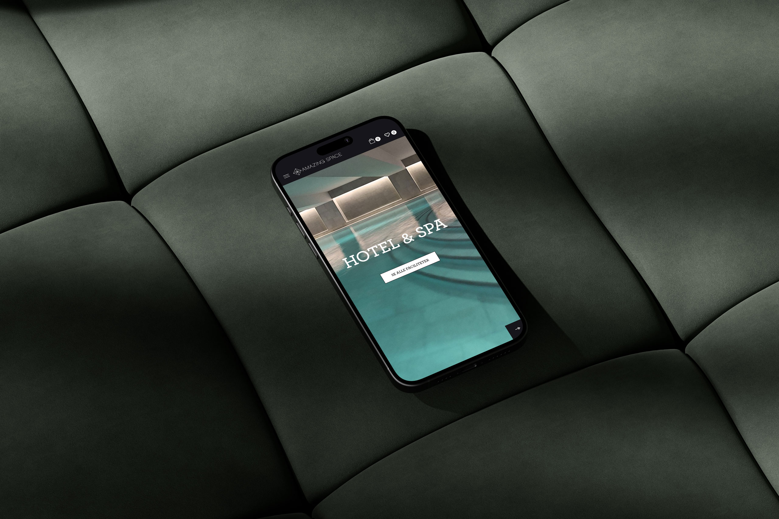 Smartphone mockup displaying Amazing Space's website design with a modern indoor pool background, placed on a dark green cushioned surface.