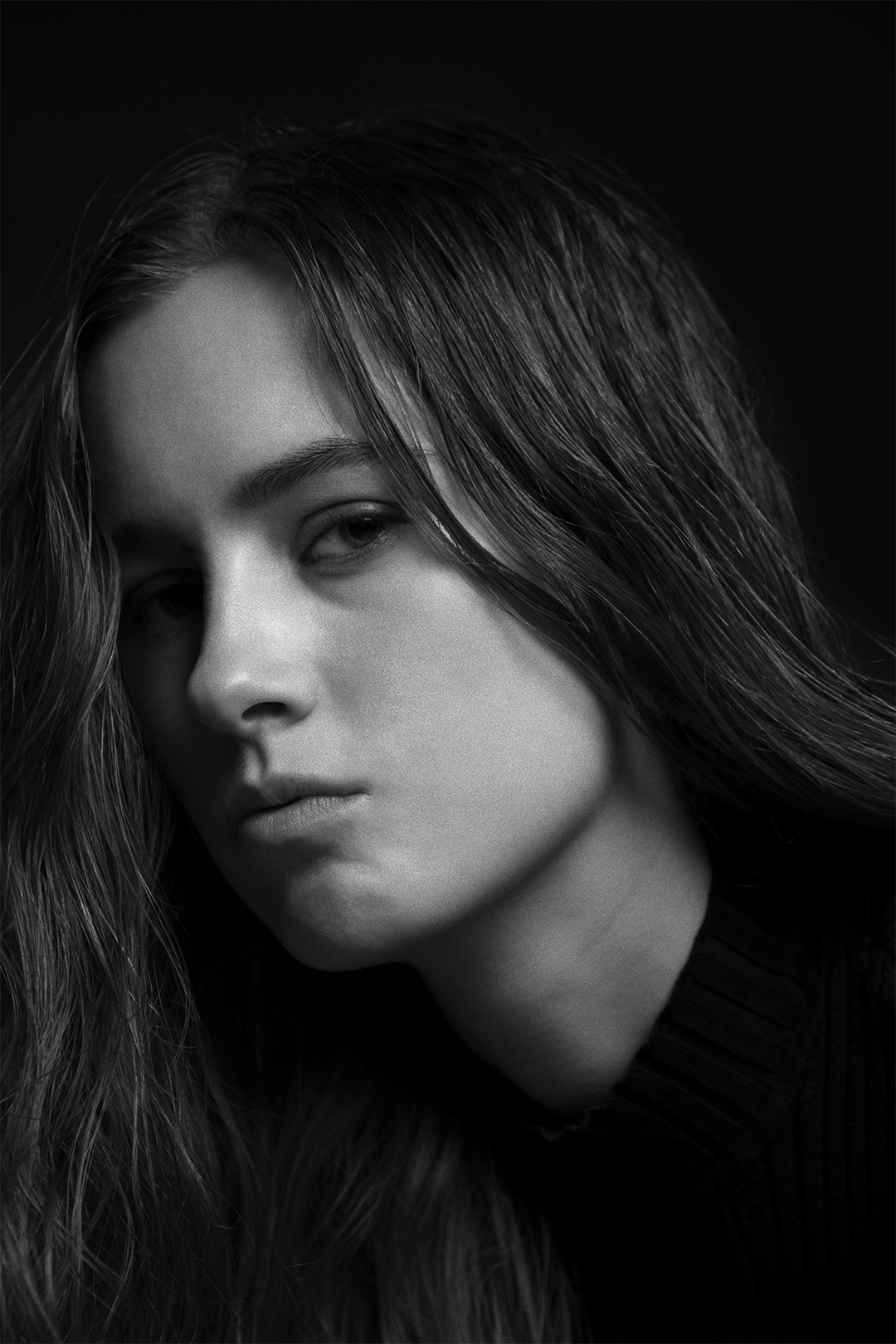 Black and white portrait photograph of Maria-May Brown with long hair, wearing a dark top, looking directly at the camera.