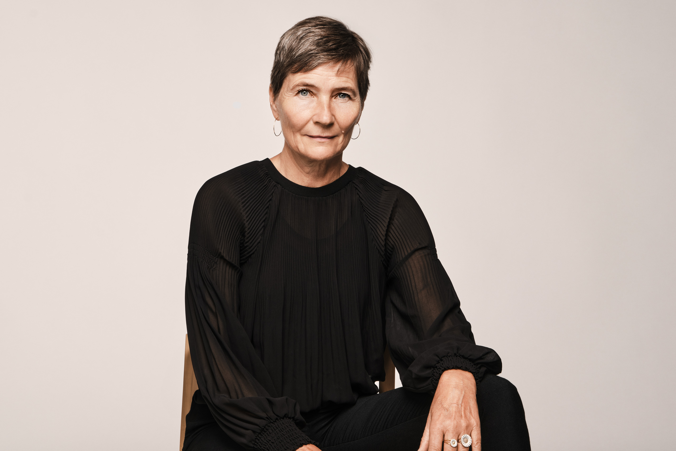 A professional studio portrait of Lene Dammand Lund, Rector of the Royal Danish Academy, seated against a neutral background, wearing a black blouse.