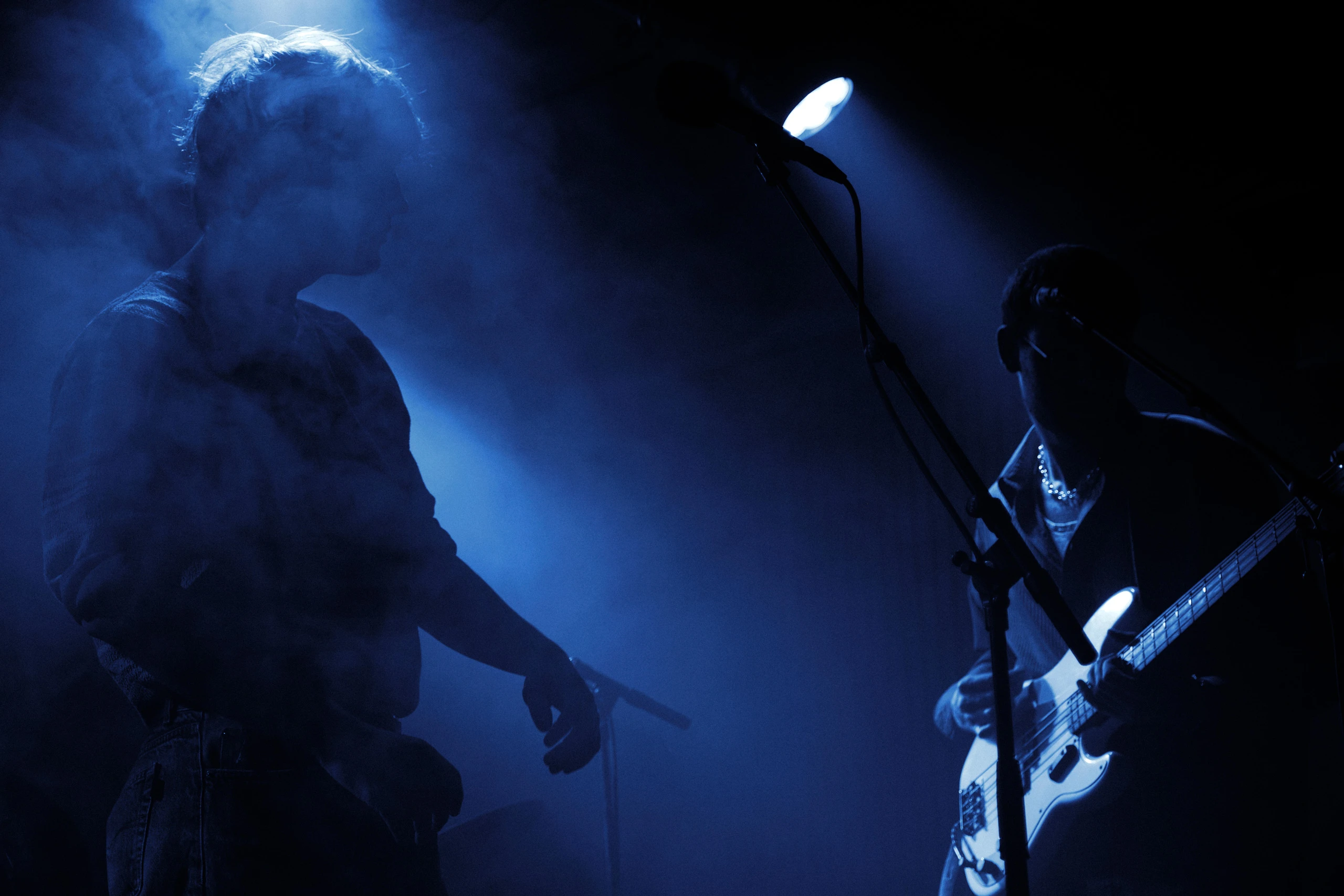 Atmospheric concert shot by Patrick Pankalla featuring a performer in silhouette and a bassist under sharp blue spotlights at Rust.