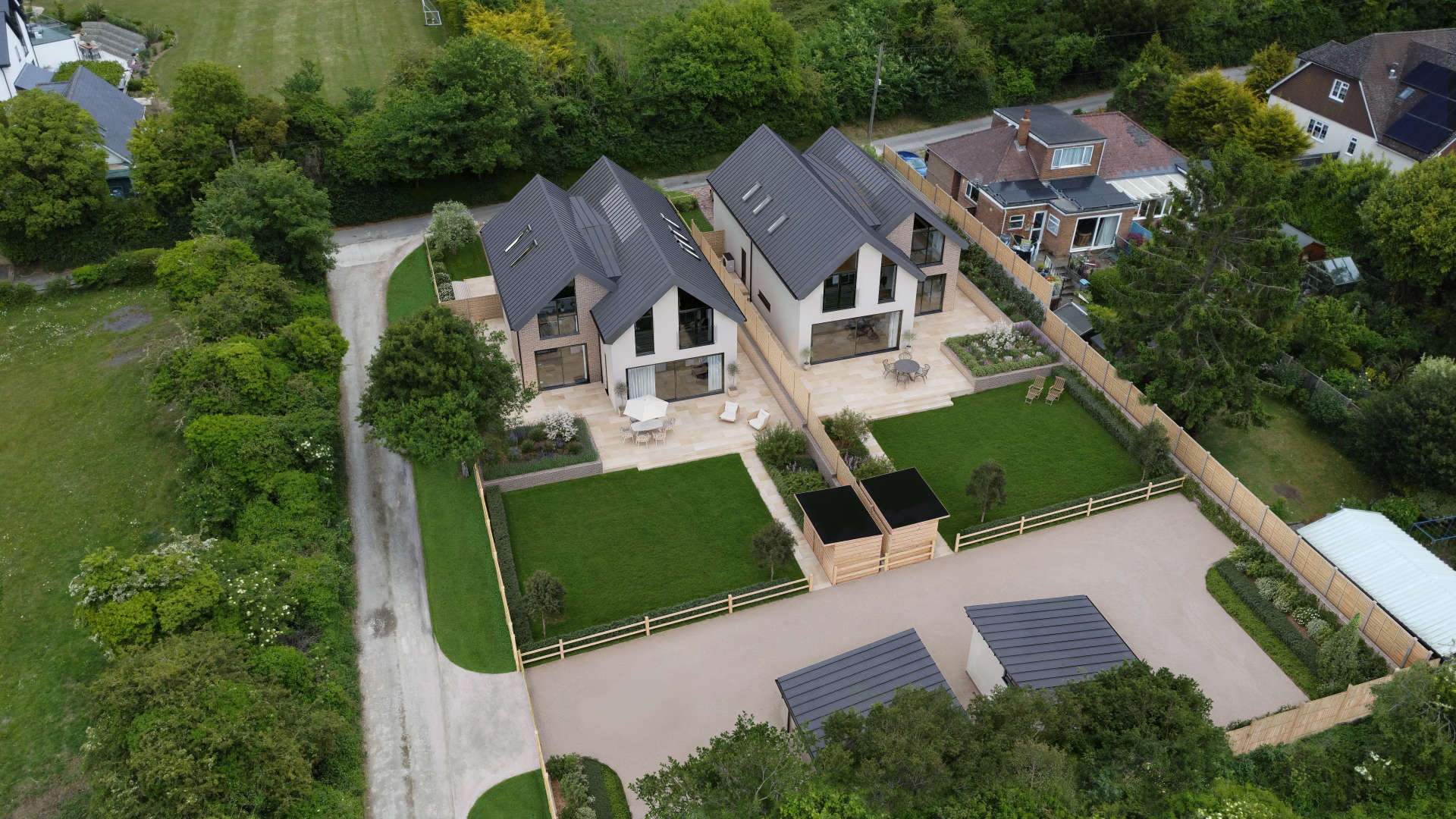 3D aerial visualisation of a contemporary residential development with two modern detached homes, landscaped gardens, and private driveways.