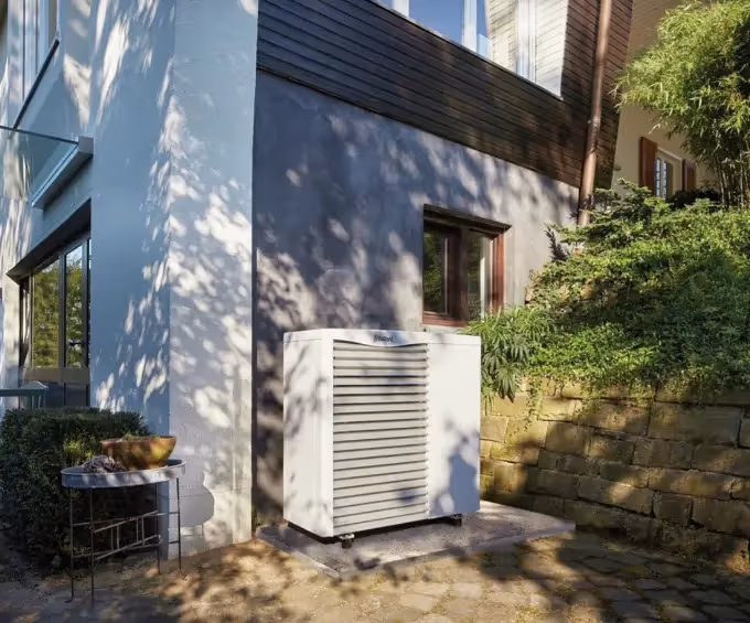 An image of a Vaillant Arotherm on a concrete base on a patio outside a home. 