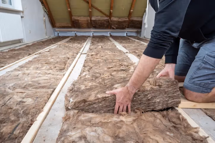A person laying insulation in a loft