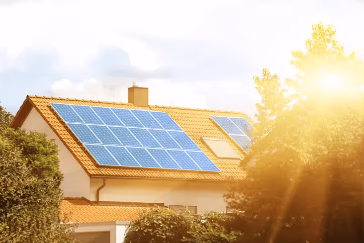 A house with solar panels with bright sunlight shining on it