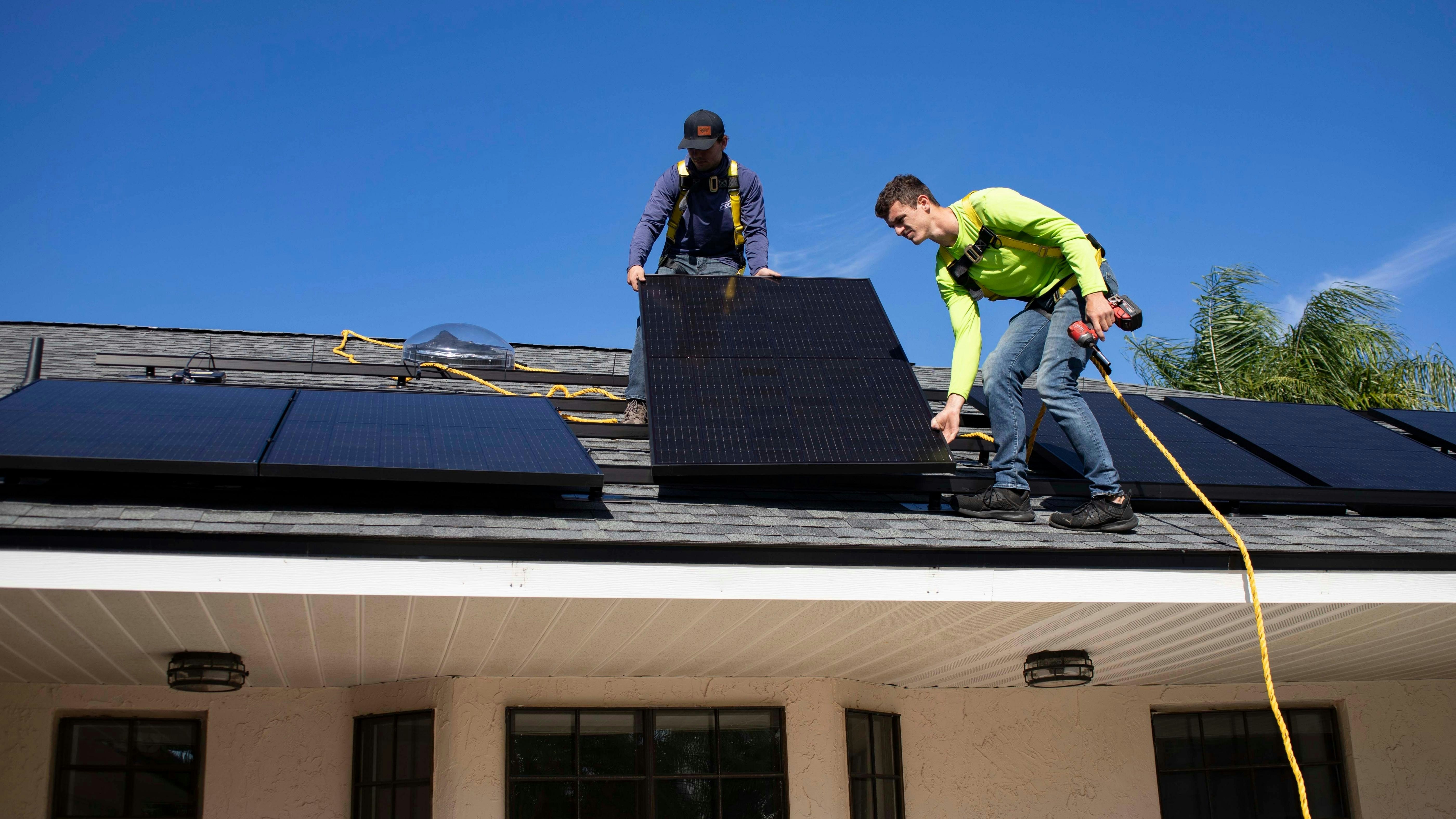 An image of installers fitting solar panels to a residential roof