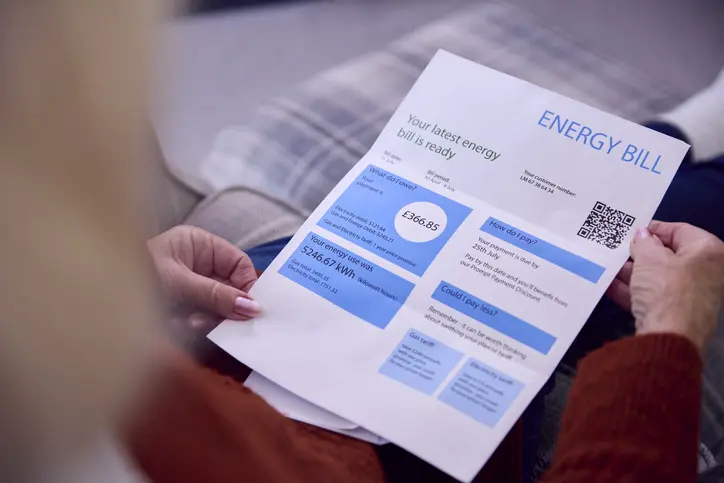 A person holding an energy bill on the sofa