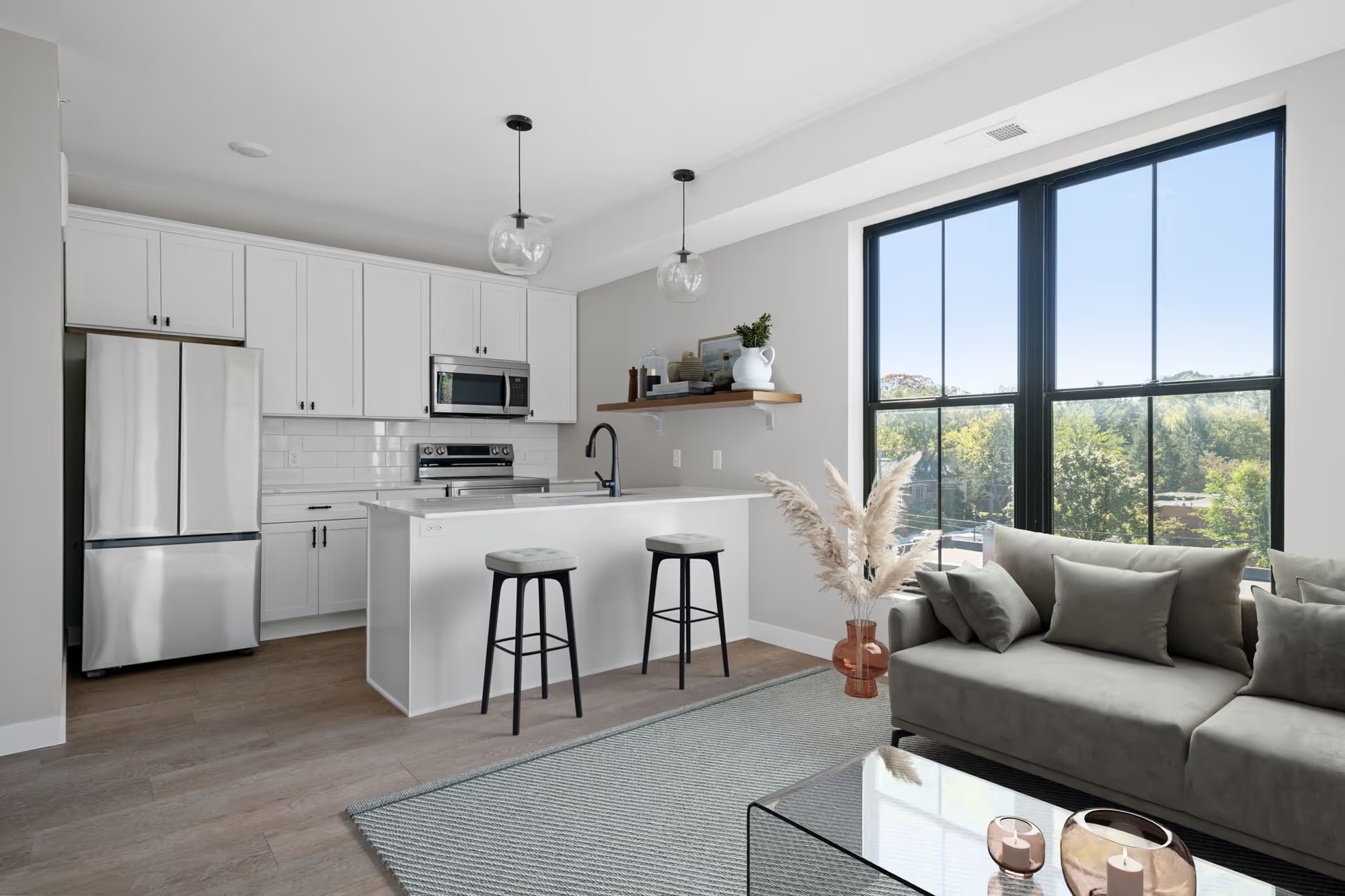 Fuller Park Flats kitchen and living area with white cabinetry, an island and tall black-framed windows.