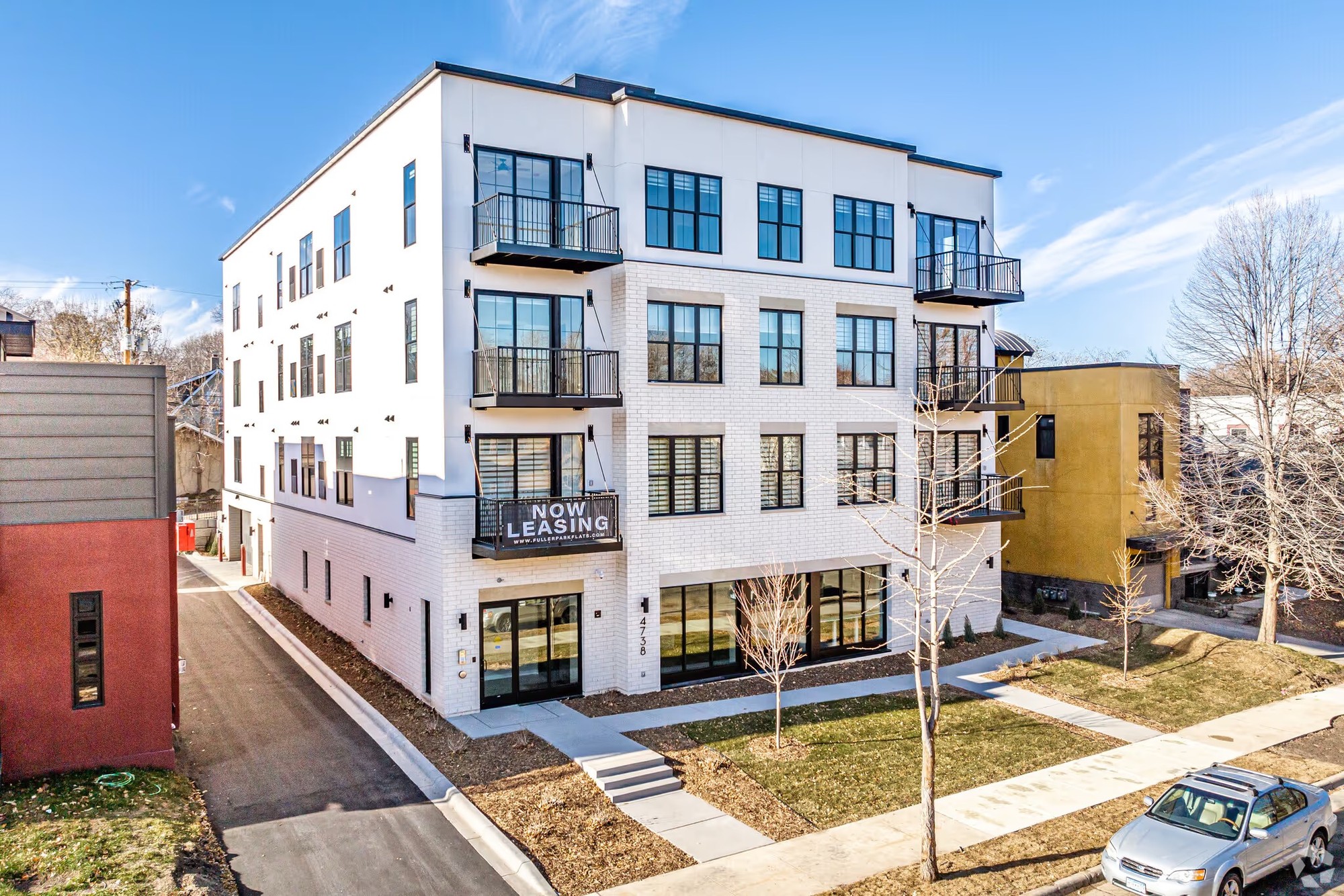 Completed Fuller Park Flats building with white masonry, black window frames and projecting balconies.