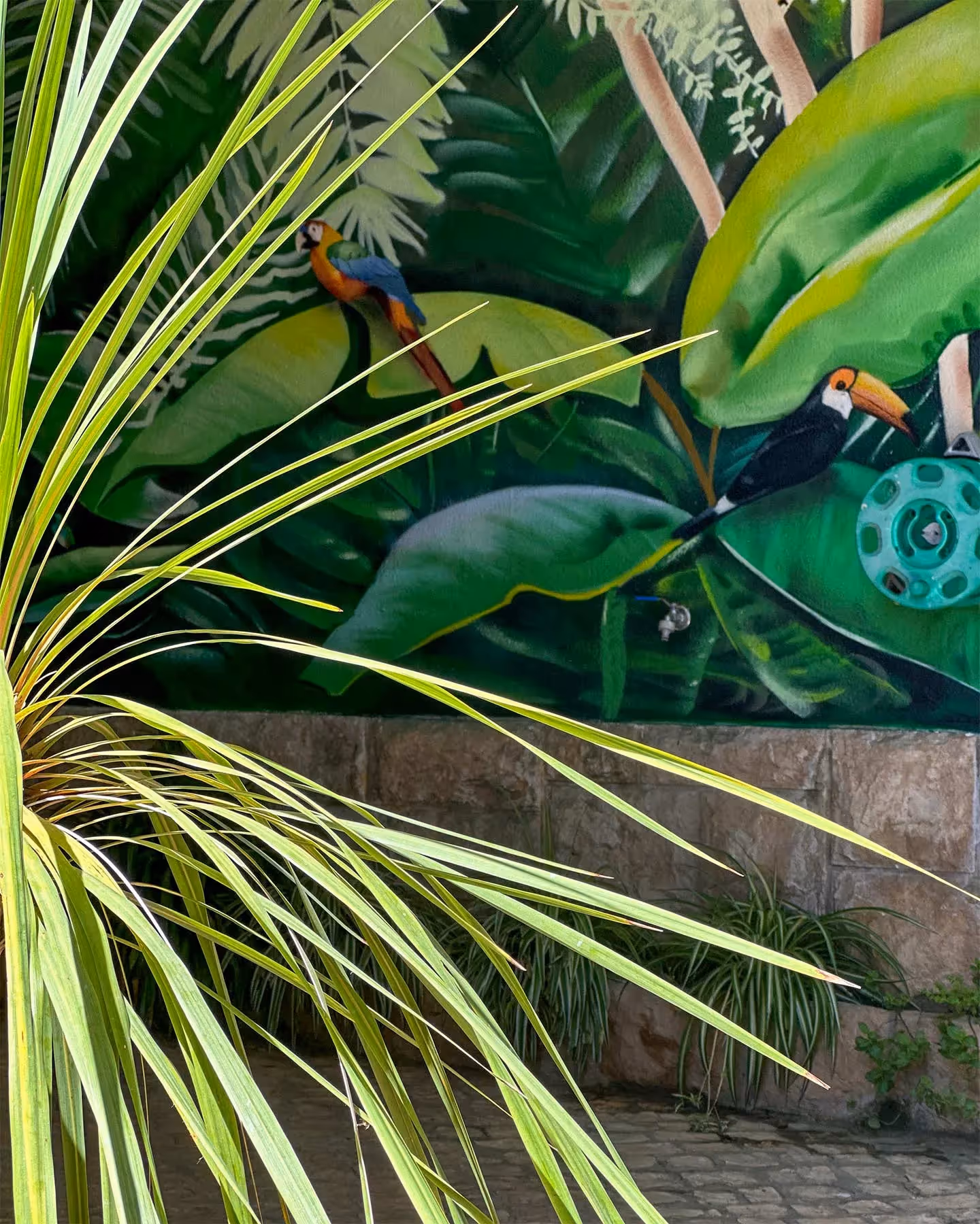Tropical leaves mural painting on the background of some leaves of a real plant