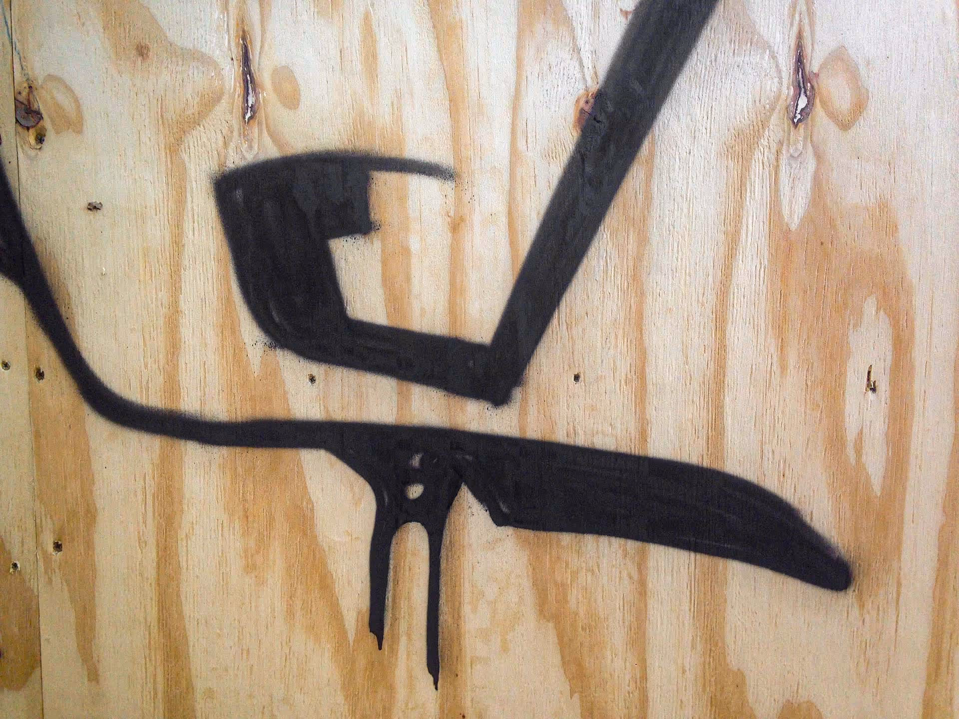 Details of an outline Kilos graffiti bombing on wood wall