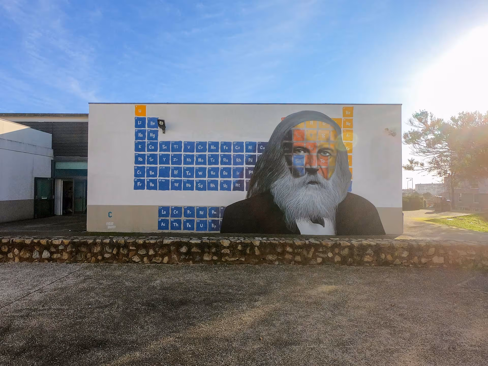 Dmitri Mendeleev's portrait painted on a wall over a periodic table