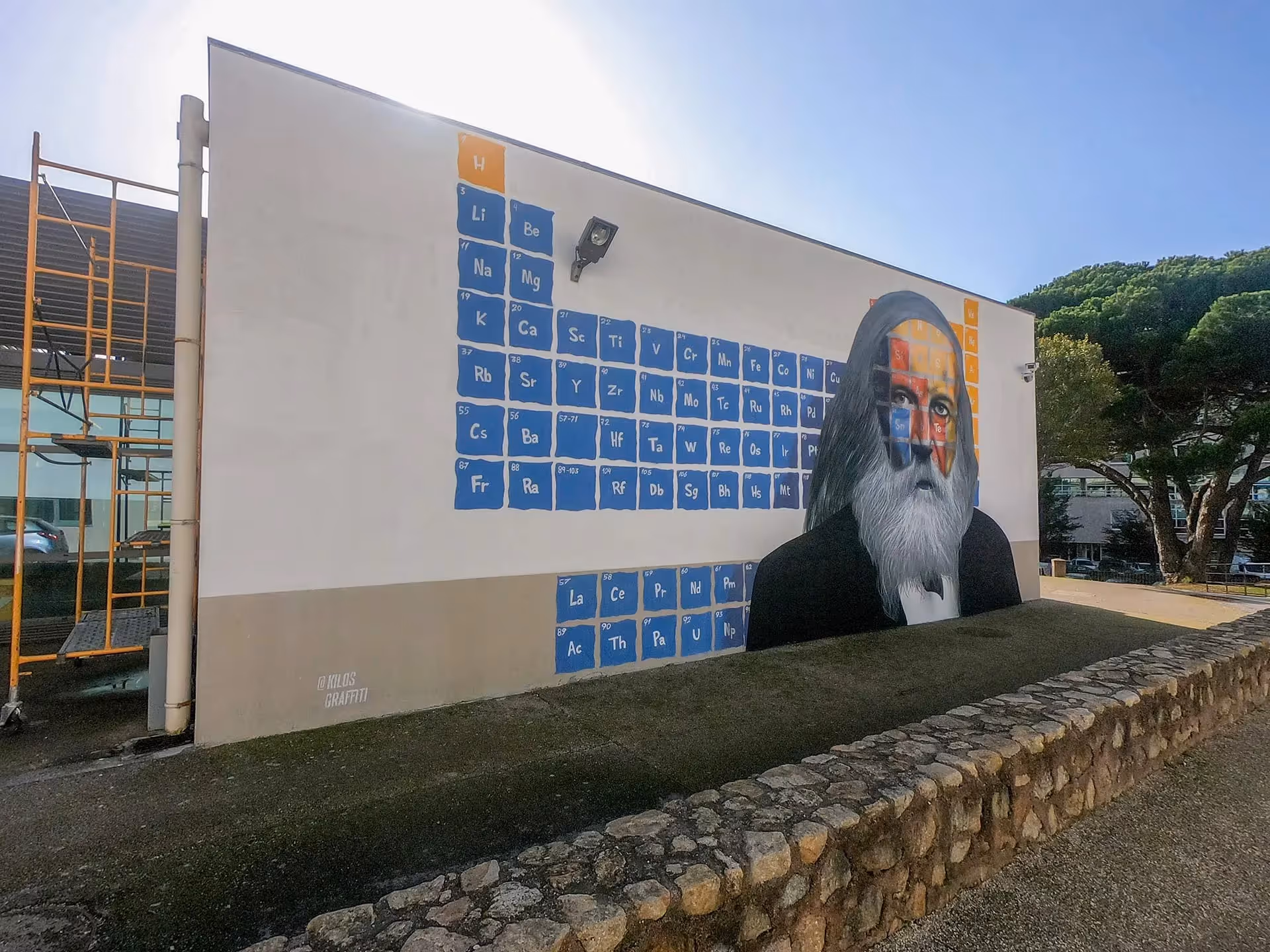 Dmitri Mendeleev's portrait painted on a wall over a periodic table