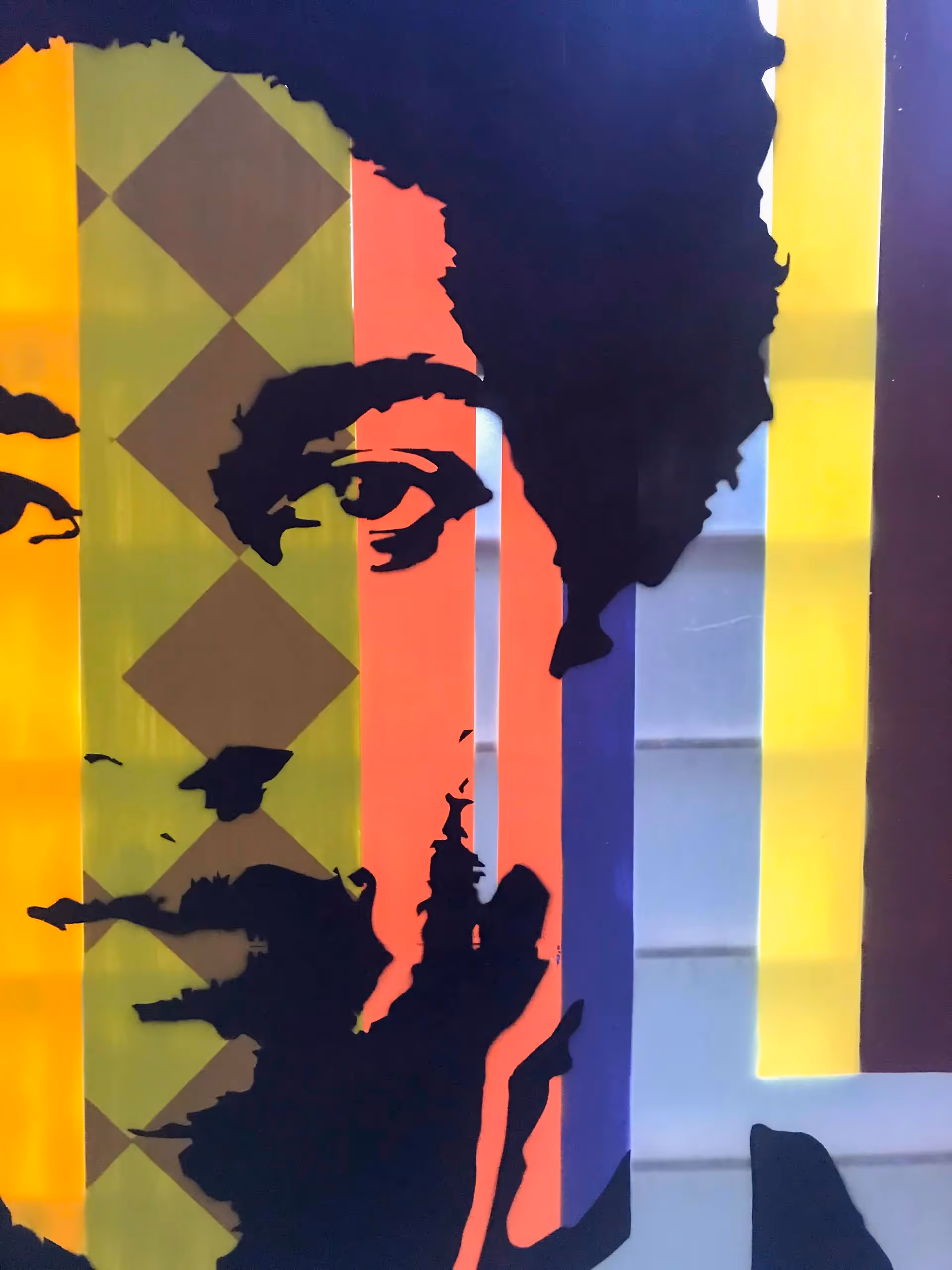 Close-up of a stencil painting of a young adult african man on top of a colorful vertical stripes background