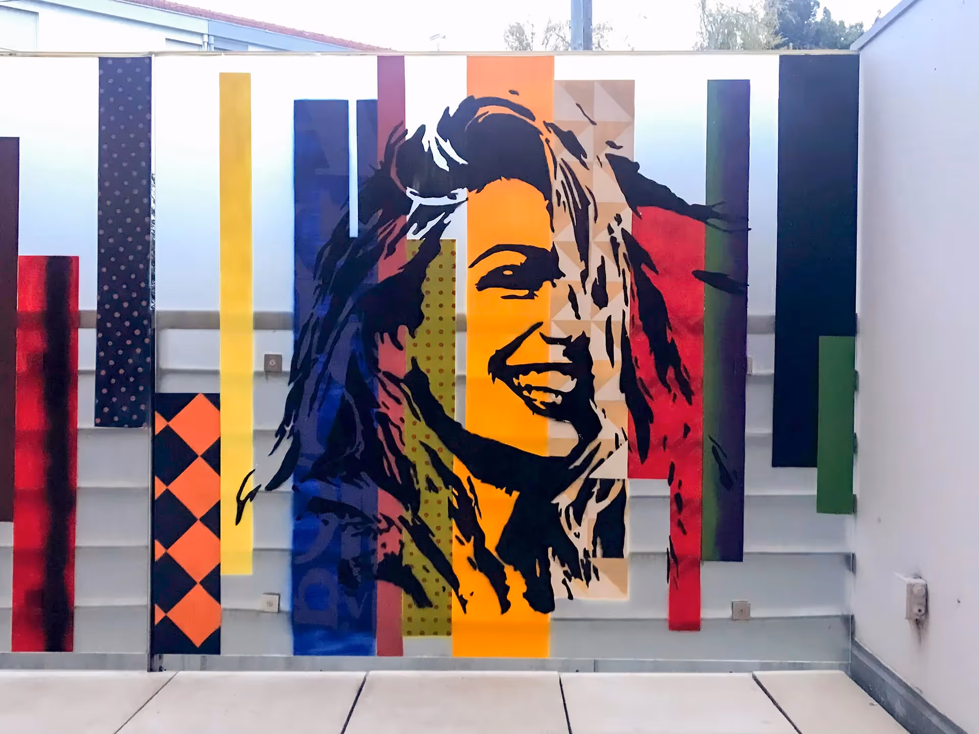Stencil painting of a young adult white girl on top of a colorful vertical stripes background
