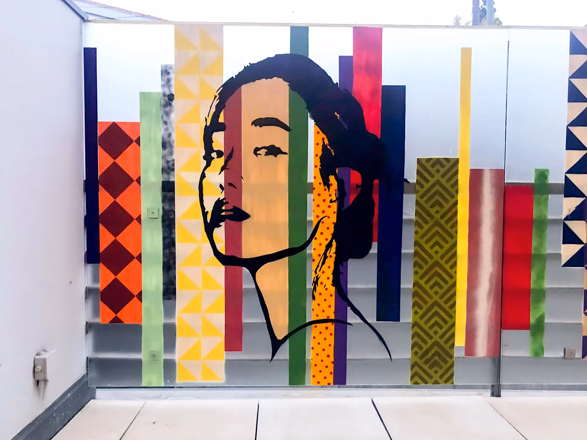 Stencil painting of a young adult asian girl on top of a colorful vertical stripes background