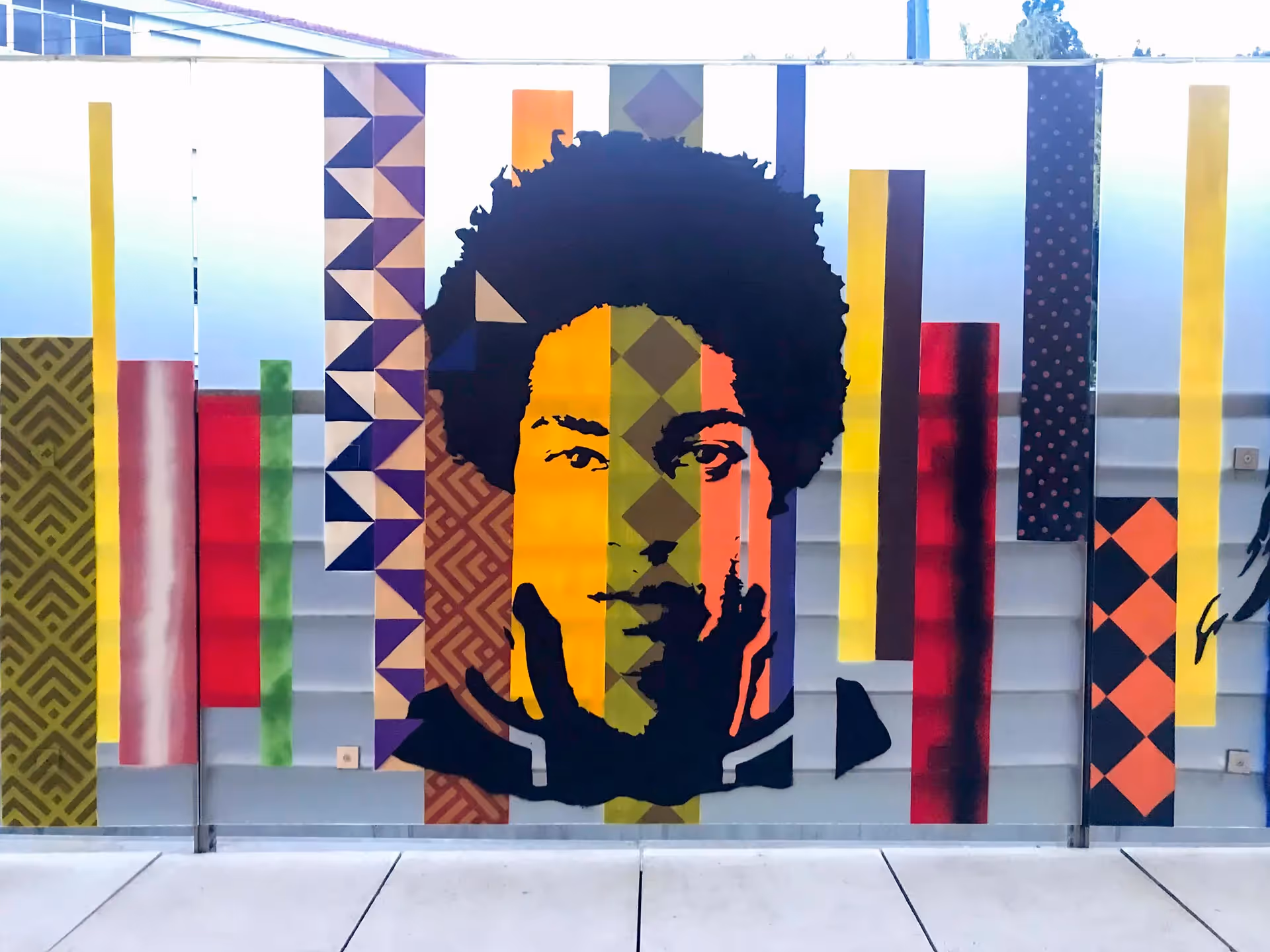 Stencil painting of a young adult african man on top of a colorful vertical stripes background