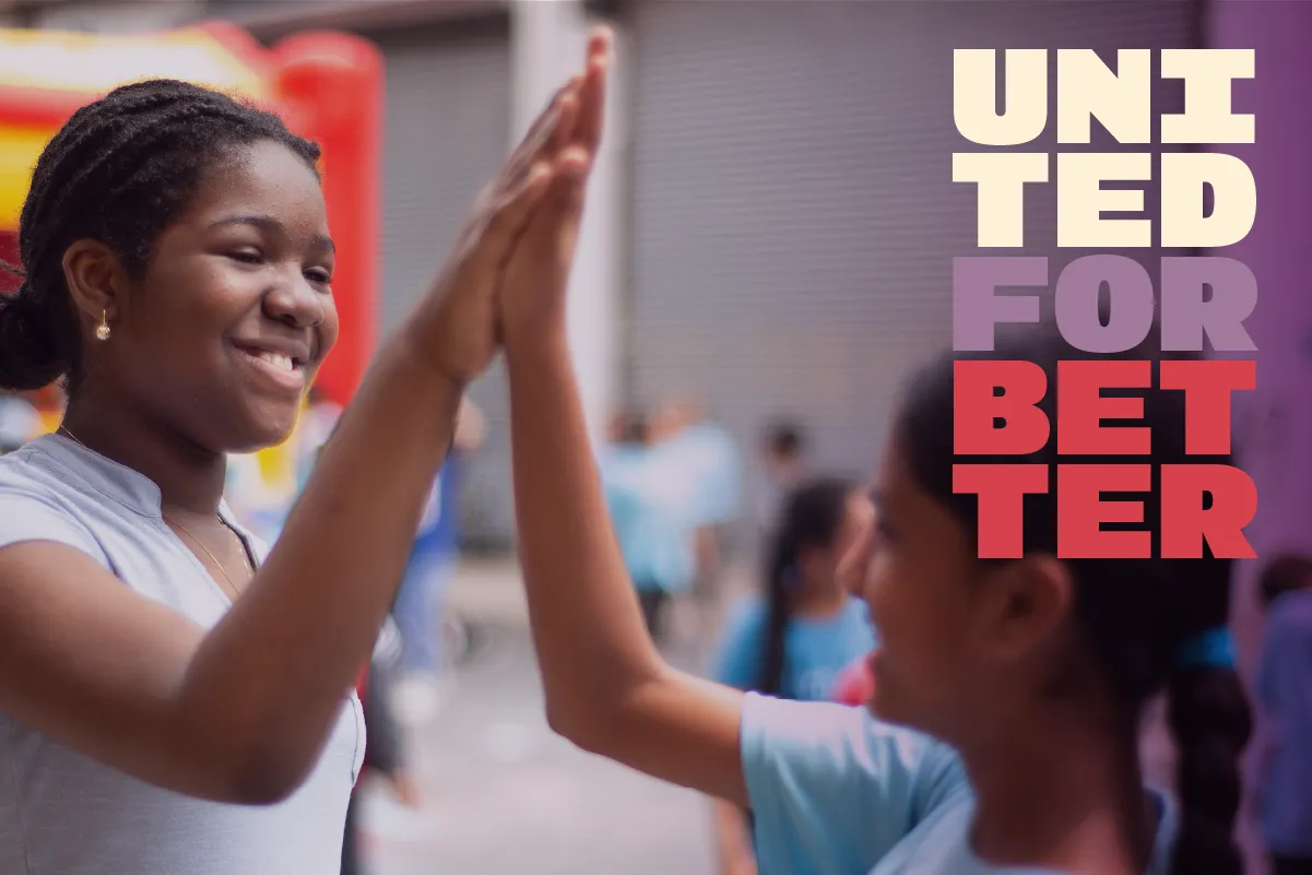 Schoolgirls high-fiving with the words "United for Better"