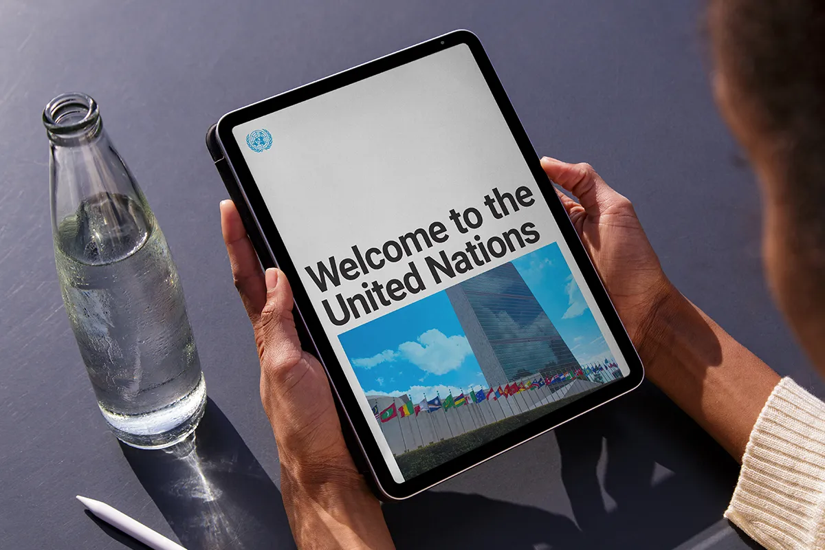 Photo of a woman holding a tablet, with "Welcome to the United Nations" onscreen.