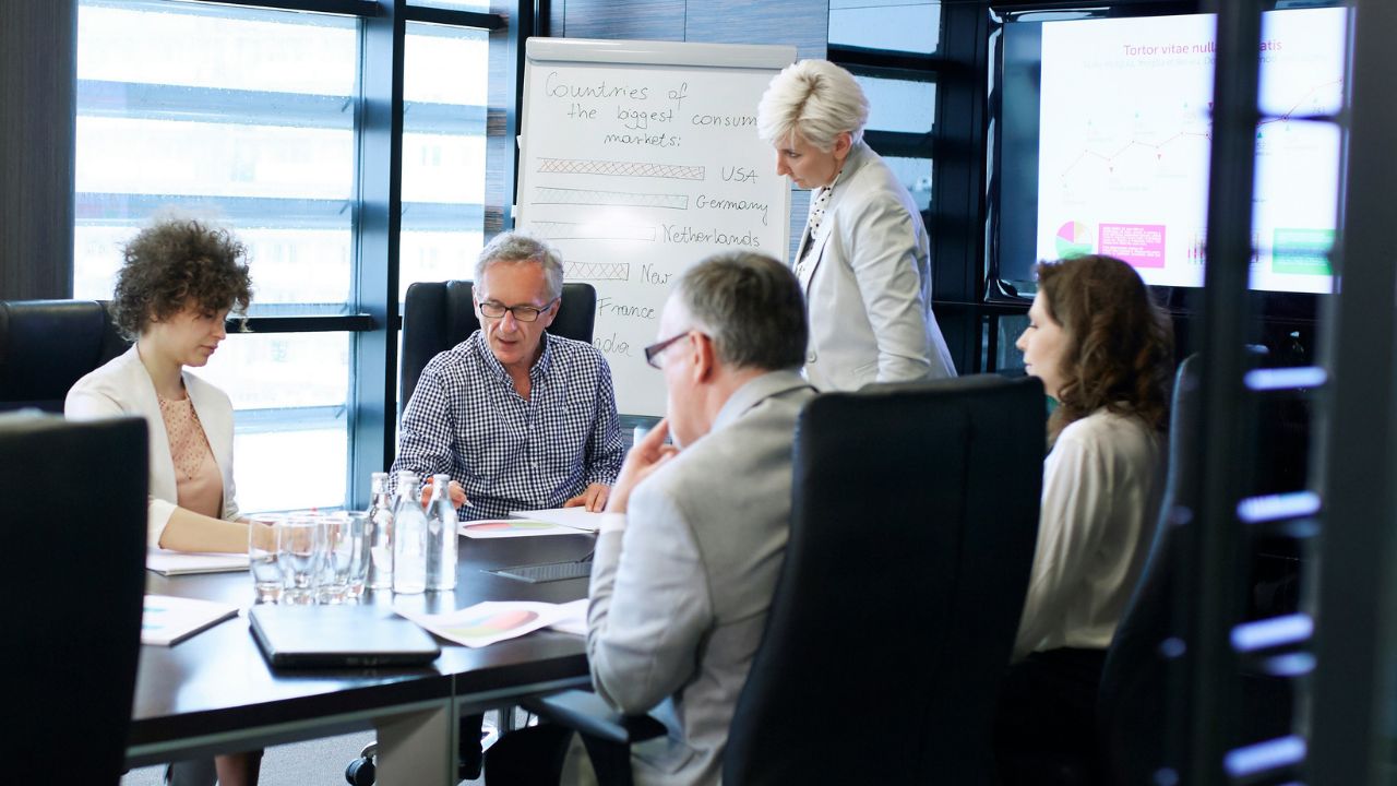 An executive addressing directors in a governance meeting — the room that convenes to decide, not to watch.