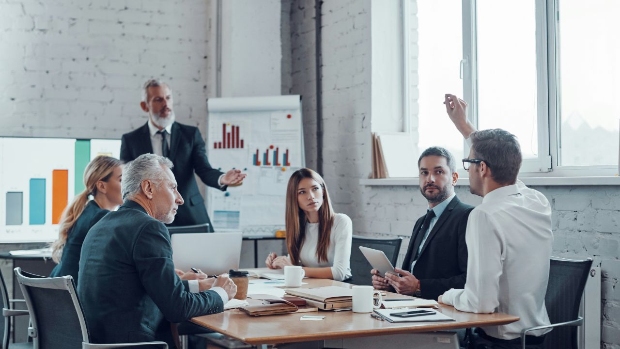 An executive pausing at the head of a boardroom table — how senior leaders hold the room in a presentation.
