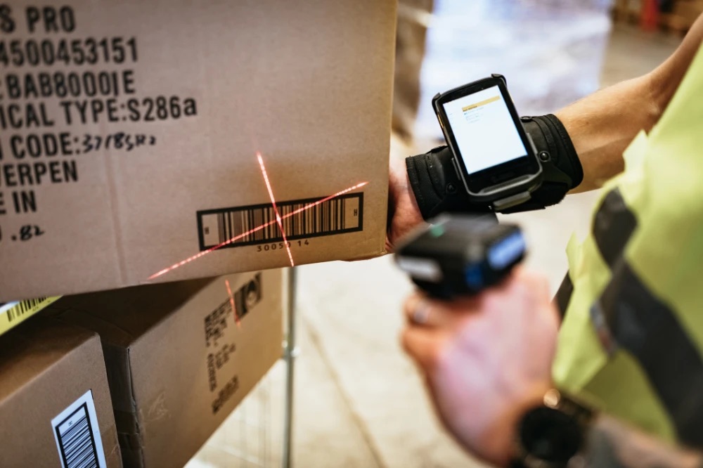 Operative scanning a carton barcode with a wearable device during a stock count, representing streamlined cycle counts
