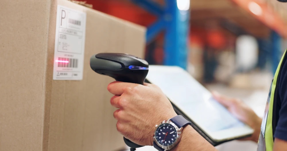 Operative scanning a labelled parcel while holding a tablet, representing automated customer charging