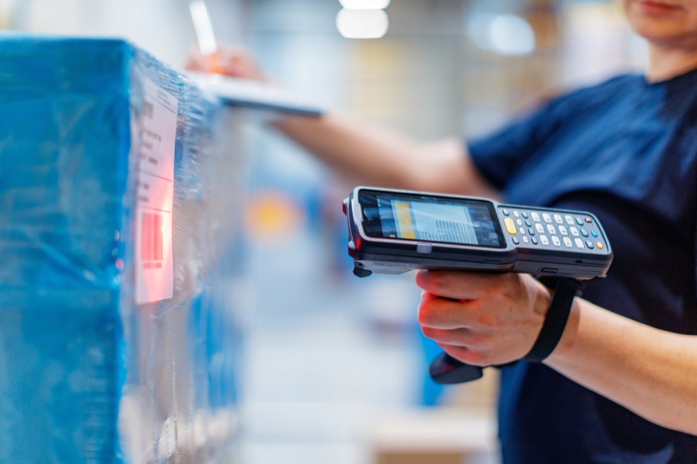 Operative scanning a barcode on a wrapped incoming pallet, representing a simplified goods-in workflow