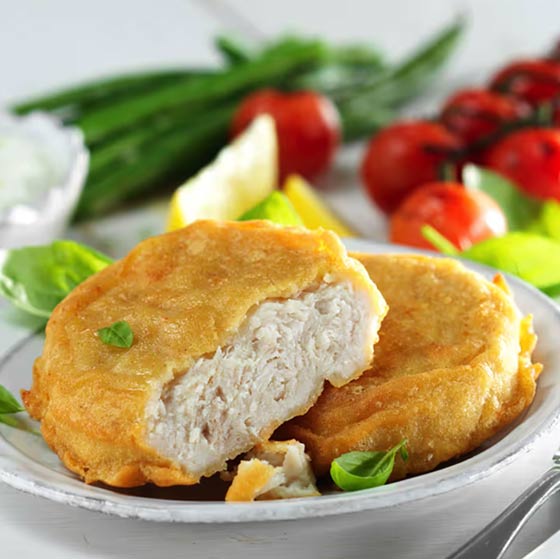 Variety of breaded and fried chicken pieces including strips, nuggets, and stuffed chicken breasts served with dipping sauce and cherry tomatoes.