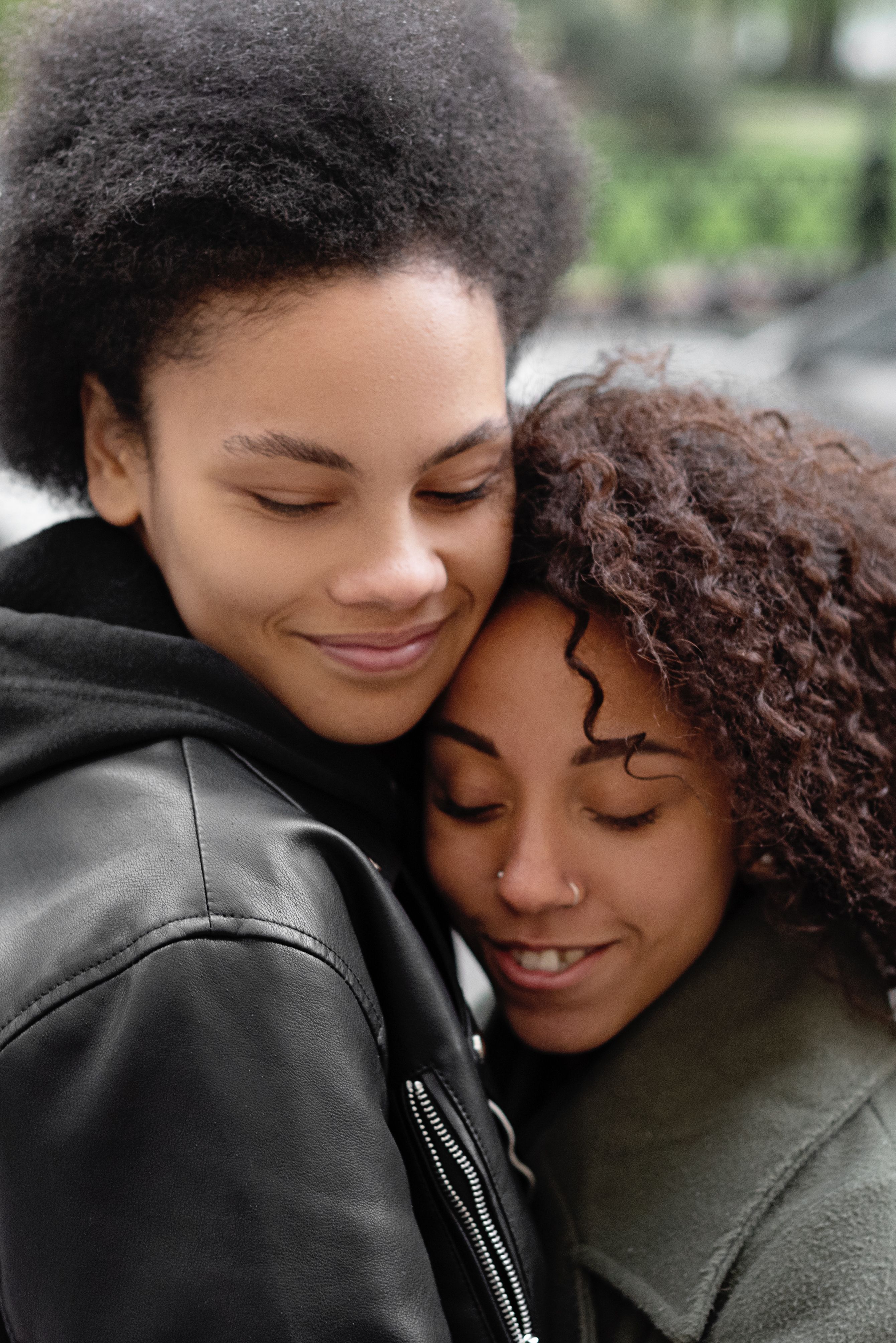Two people with short dark hair in a comforting hug.