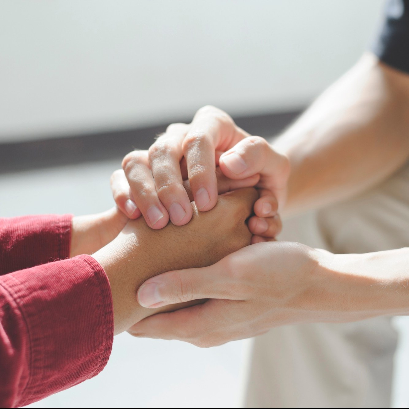 Close-up of two people holding hands in support.