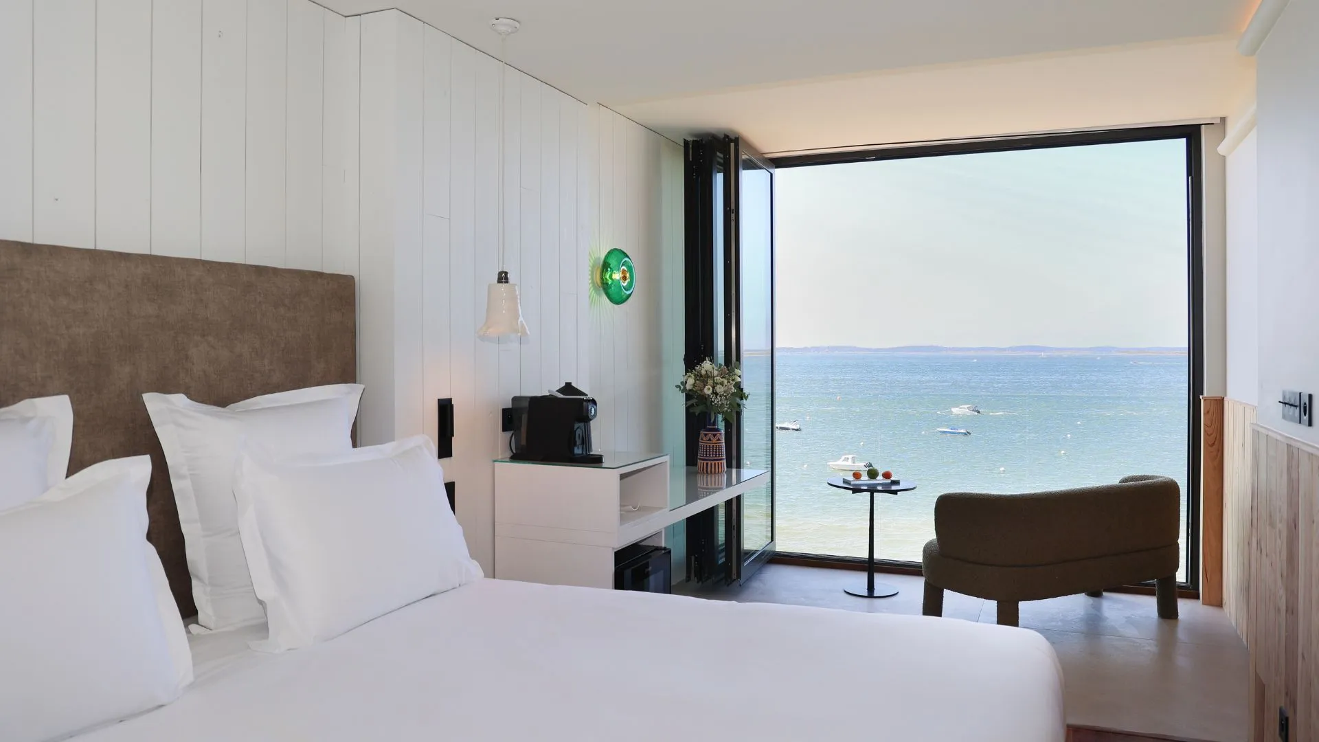 Habitación Deluxe del hotel Les Vagues con cama king-size, decoración refinada y terraza privada con vistas panorámicas a la bahía de Arcachon.