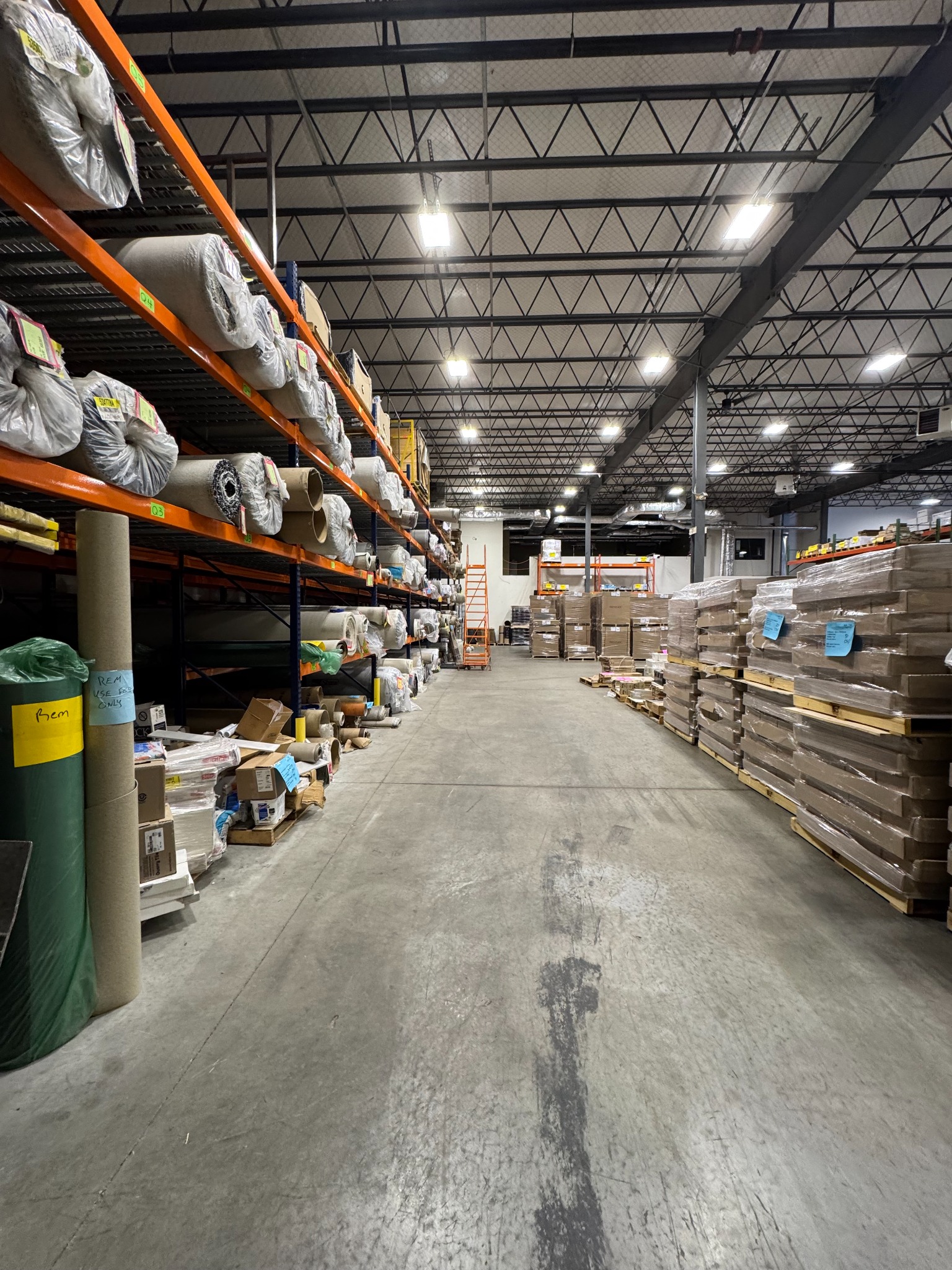 Carpet rolls and palletized flooring materials in the Pro-Tech Floors warehouse