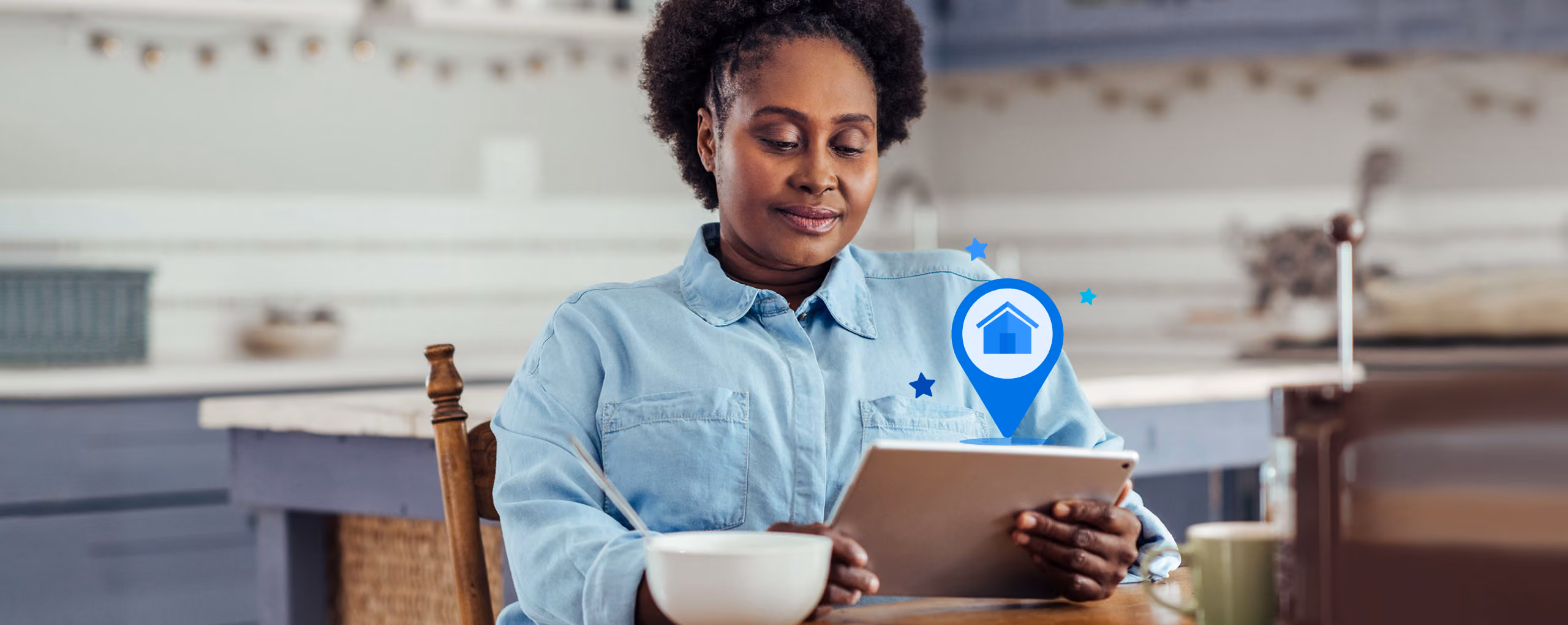 Woman sitting at kitchen table looking at a tablet with a digital home location icon above it.