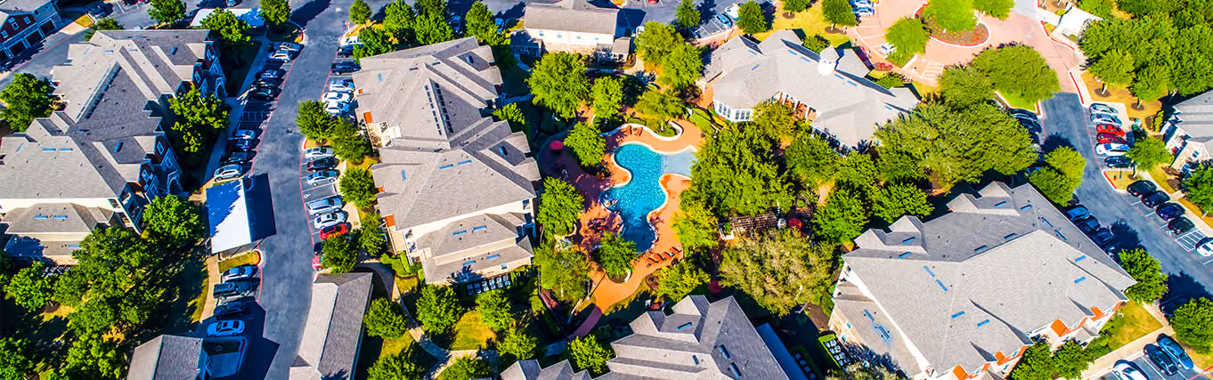 birds-eye-view of apartment complex with a pool and trees