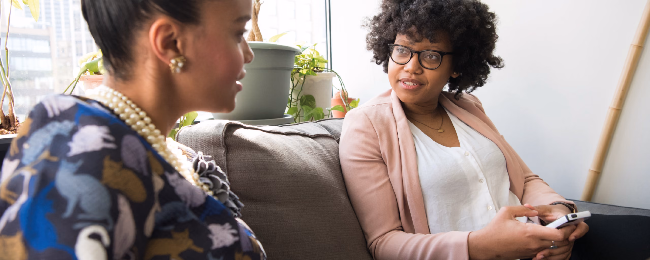 real estate agent sitting on the couch talking with prospect|mockup of real estate website|photo of real estate agent at an open house with a couple|photo of real estate agent showing house to expecting couple|prospecting postcard download button